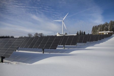 Tipos de energías renovables: cómo funcionan y dónde se usan Paneles solares y un aerogenerador en un paisaje nevado