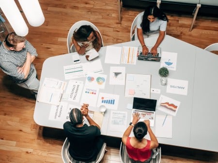 Cómo hacer un plan de marketing digital: pasos y un ejemplo Equipo planifica una estrategia de marketing digital con gráficos y portátiles