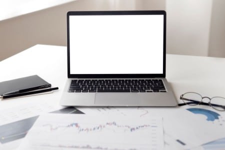 Ordenador portátil y documentos financieros sobre una mesa de trabajo
