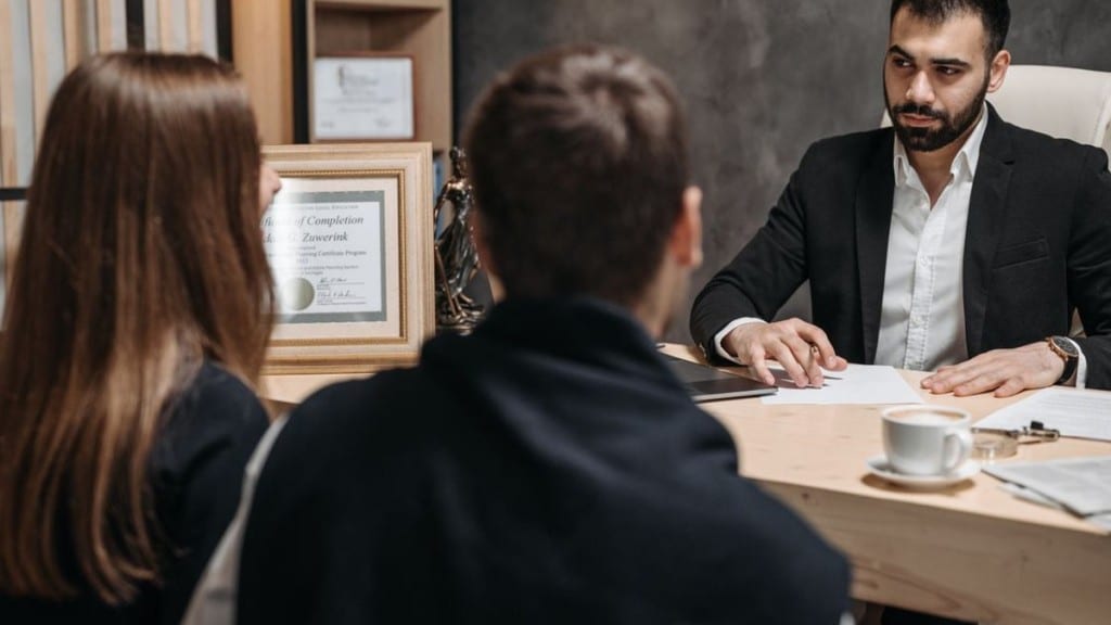 Psicólogo forense: qué hace, cómo trabaja y qué formación necesita Profesional entrevistando a dos personas y revisando documentación