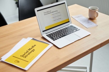 Plan de contenidos en redes sociales y calendario editorial Ordenador y documentos para elaborar un plan de contenidos en redes sociales